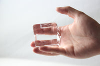 A hand holding a large clear ice cube