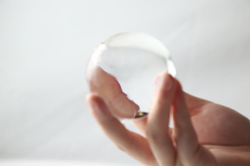 A hand holding a large clear ice sphere
