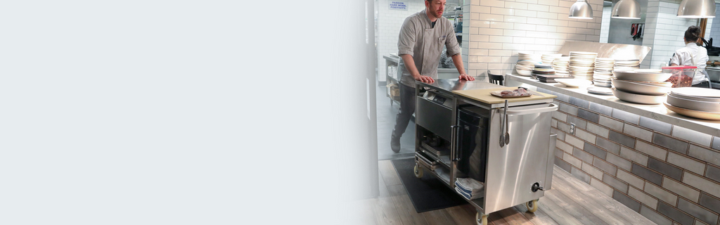 A chef pushing a cart in a restaurant kitchen.