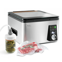A picture showing a silver and black box-style chamber vacuum sealer with a glass lid and a vacuum adapter on a mason jar with pickles and some vacuum-packed meat next to it. 